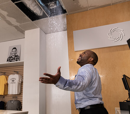 Manager of a retail shop looking up at his leaking ceiling