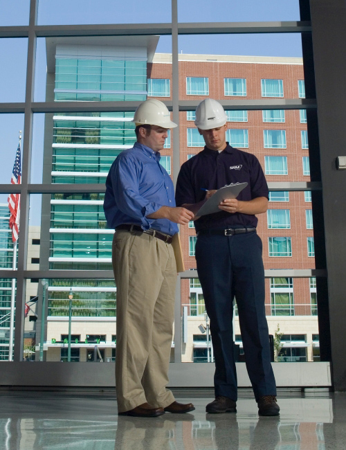 Two men referencing paperwork on job site. 